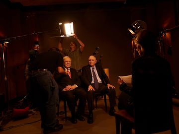 Two elderly gentlemen in suits and ties at a photo shoot