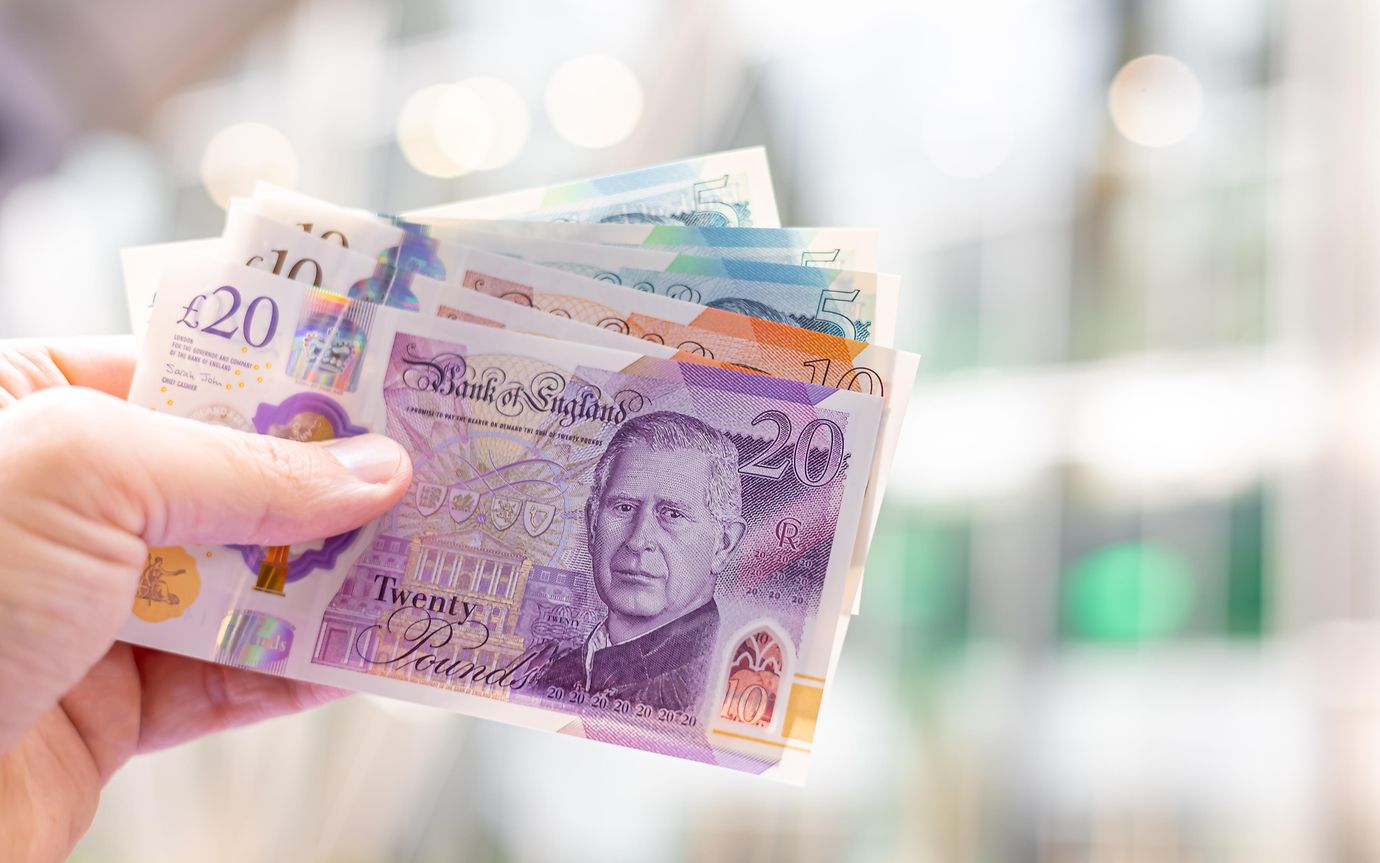 hand holds selection of British sterling notes